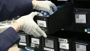 A person in white gloves is putting something into a box.